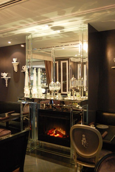 The mantle of the mirrored fireplace is topped with an assortment of crystal ornaments and candleholders.