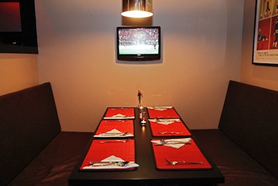 Booths include mounted flat-screen TVs and hanging lights.