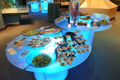 A spread of smoked fish, chilled shrimp, scallops, clams, and oysters rested on glass tables lit with soft blue lights.