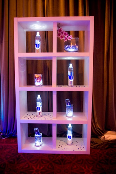 Two shelving units in the reception lounge displayed Smartwater bottles lit from below and orchids in square glass vases.