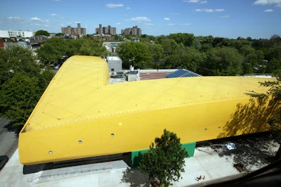 The new building, which forms the façade of the museum, is an L-shaped, two-story structure covered in yellow tiles.