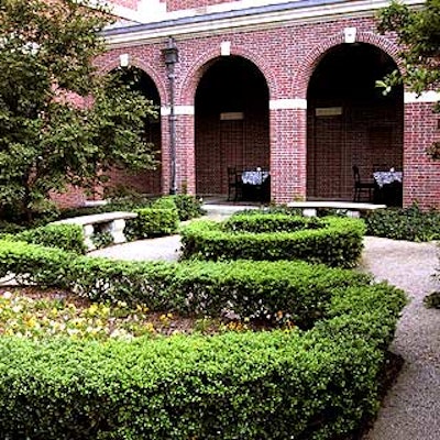 The front garden features carefully manicured hedges encircling simple flower gardens.