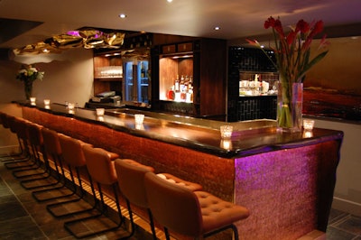 The bar, made out of African Bubinga hardwood, is wrapped in Maya Romanoff's mother-of-pearl wallpaper.