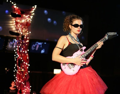 Collaboraction company members dressed as rock stars, posing with blow-up guitars on elevated platforms throughout the venue.