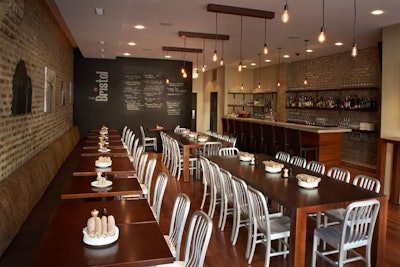The main dining room seats 55 and features hanging Edison bulbs, tan leather banquettes, and two communal tables.