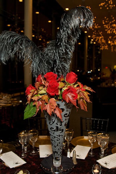 The Floral Studio topped tables with vases of red roses and black feathers.