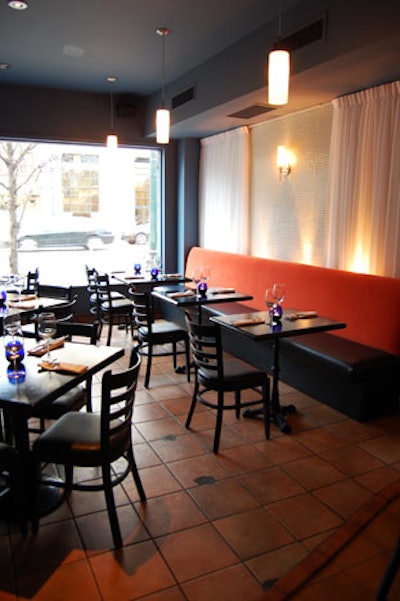 White glass-tiled walls, black furnishings, and terra cotta tiles fill the dining room.