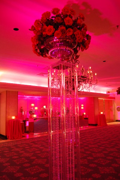 Bouquets of red roses topped stands with hanging crystal beads at the cocktail reception.