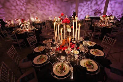 Tables sheathed in black satin held silver candelabras, petals, and arrangements of red roses.