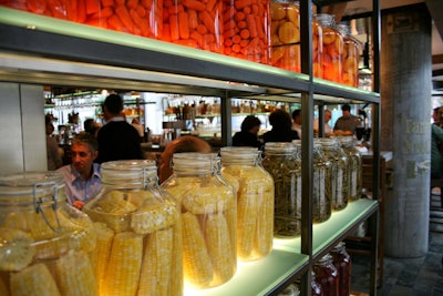 Shelves holding large jars of preserved fruits and veggies function as a room divider.