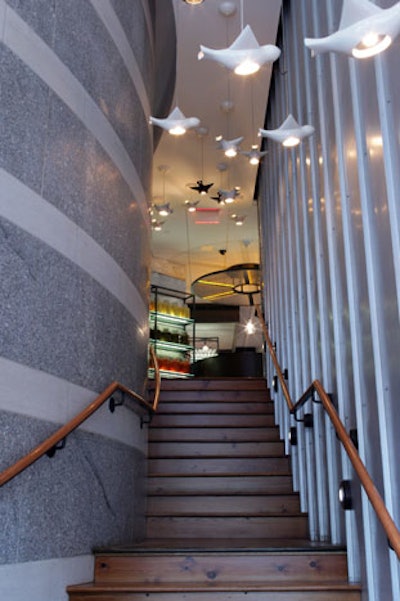 The staircase to the mezzanine features a wall of salvaged steel and a bird-shaped light fixture.