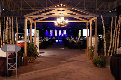 At the entrance to the dining area, two antler chandeliers hung from a wooden structure surrounded by greenery and birch branches.