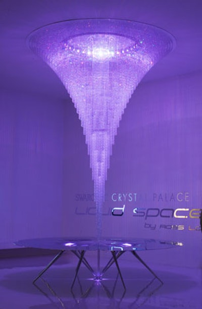 The Swarovski Crystal Palace featured a vortex-shaped crystal chandelier that appears to have melted through the ceiling and the middle of the table below, with color-changing LED lighting embedded in the crystals