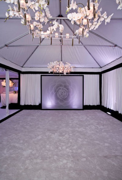 At the entrance to the tent, Wendt framed a piece of sheer fabric imprinted with an image of a camellia and created chandeliers with votives and test tubes of white orchids.