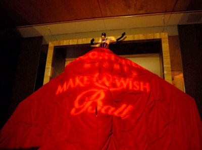 Triton Productions employed an opera singer to perform perched above the doorway to the ballroom-through which guests would later enter-at the 13th annual Make-a-Wish Ball in Miami, with her long custom-made red skirt cascading over it.