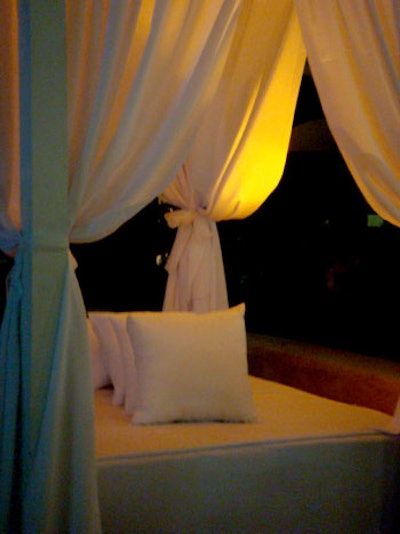 Custom beds with decorative wood frame canopies, white curtains and oversized pillows served as seating in the plaza.