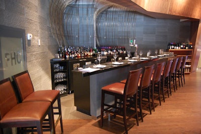 Walnut paneling surrounds the bar, which features a black countertop inspired by piano keys.