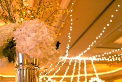 Ornate silver vases filled with white hydrangeas accented by bursts of sunshine yellow botanicals topped each table.
