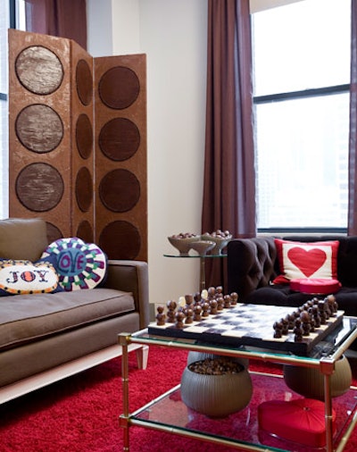 A screen dominates the living room area, which also includes a chocolate chess set and bowls of Godiva candy.