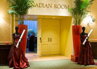 Two mannequins, dressed in floor-length red gowns and holding scrolls of paper, flanked the entrance to the dining room.
