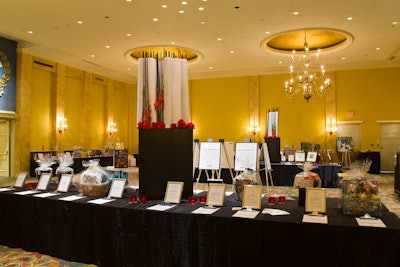The silent-auction room featured large floral arrangements, created by Solutions With Impact, with red roses and scrolls of printed paper.