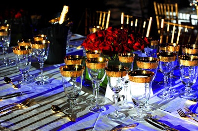 Tables were draped in crisp white linens and adorned with gold place settings, and tightly bound red rose centerpieces.
