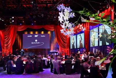 Red draping and a screen were onstage during the beginning of dinner, before the presentation space transformed into a stage for entertainment.