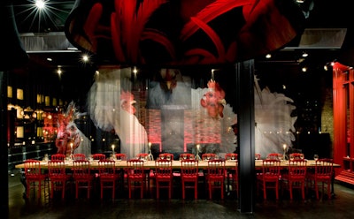 Plush red chairs line either side the the communal table, which features hand-carved aluminum legs inspired by different birds.