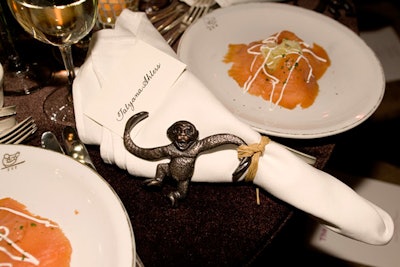 Ornaments of swinging monkeys attached to a raffia tie topped napkins at the table by William Meyer and Charles Feltner for William-Wayne & Company.