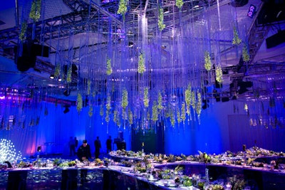 Suspended glass vessels accented with fresh flowers hovered over the dinner and award space.