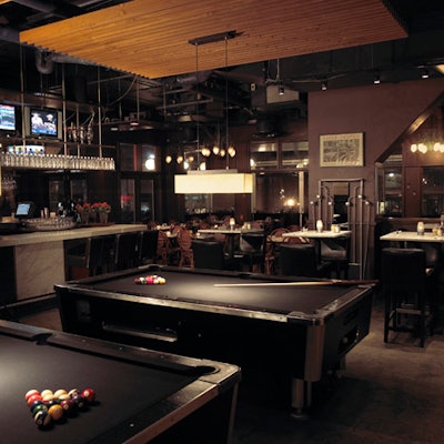 A wall mural has been added to the billiards area, which features solid teak paneling and two black cloth pool tables.