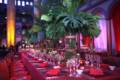 Opulent floral arrangements—comprised of dark red Mokara orchids, heliconia, and palm fronds—topped each table.