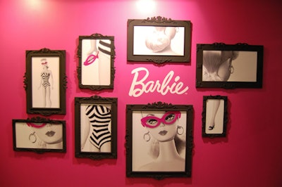 Framed images of Barbie hang on a pink wall at the entrance to the shop.