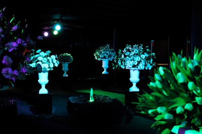 Guests entered the event via a dimly lit walkway filled with white floral arrangements.