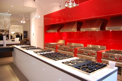 Wolf's cooking appliances are displayed in an area with red light sculptures and red glass walls.