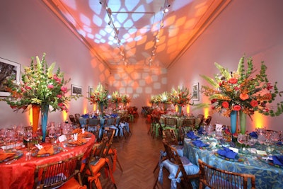 One of the evening's brightest rooms, Gallery 1 had neon blue, orange, and green settings and lighting. A trio of vases held loose arrangements of pink and yellow blossoms. Adding to the fun: rustic bamboo folding chairs and paper cutouts embedded with seeds in the shape of dragonflies on each setting.