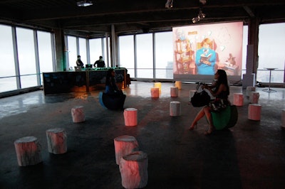 Near a video display, guests listened to the DJ on colorful fan-shaped rocking chairs and white tree stumps used for seating.