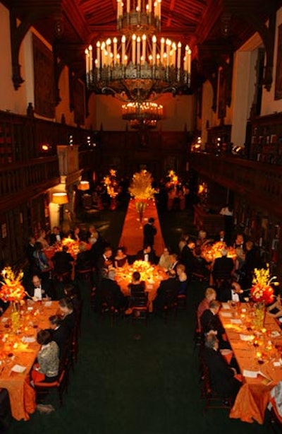 Spotlit centerpieces of red roses, yellow orchids, and forsythia branches sat on glass platforms that towered over each table.