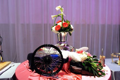 Floral arrangements with feathers and bike parts topped tables throughout the room.