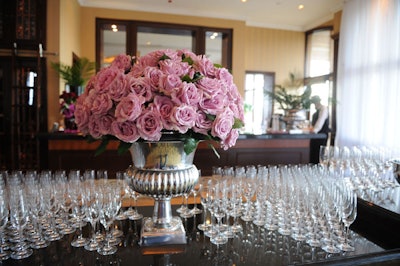 A silver vase filled with pale purple roses sat amid champagne glasses on a display where servers offered Louis Roederer Cristal champagne to guests.