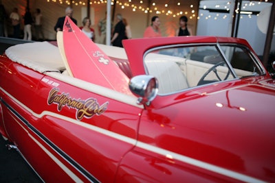 A vintage convertible carrying surf boards and emblazoned with the words 'California Girl' tied into the theme.