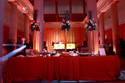 The long banquet table of desserts included six-foot-tall centerpieces of pink roses, green orchids and tall grass in a glass cylinder filled with orange gel.