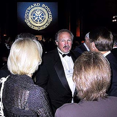 Newly installed Outward Bound president Richard Bangs posed against Scharff Weisberg's video screen showing the Outward Bound logo.