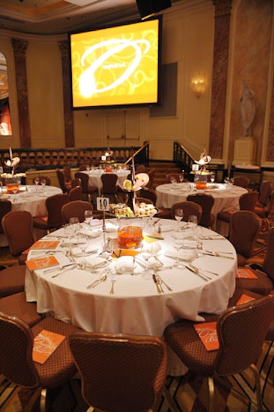 Centerpieces consisted of vases filled with orange liquid and floating white flowers, topped by a dessert tray.