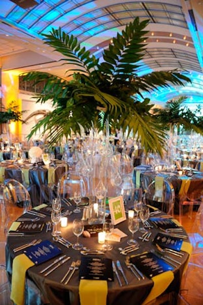 Solutions With Impact topped tables with two different centerpieces: glass vases filled with palm leaves and arrangements of white carnations.