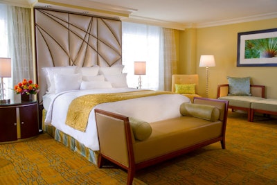 The bedroom of the Washington presidential suite has a custom headboard and decor in shades of gold and platinum.