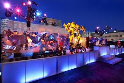 At the party, the Bumble Bee Transformer character stood surrounded by an illuminated metal sculpture wall.