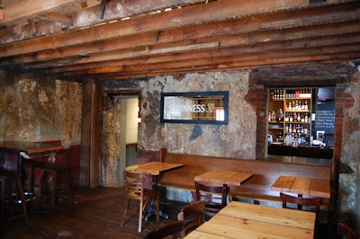 The cottage room, which dates to 1884, has exposed ceiling beams and cracked stone walls.