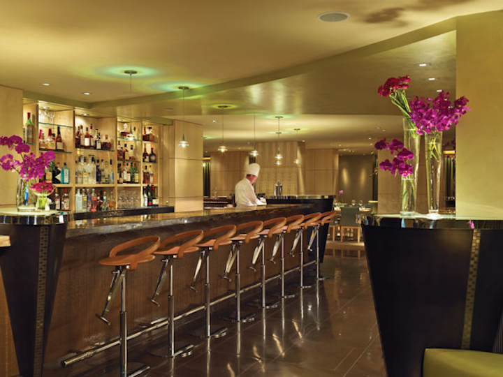 The tiger-eye marble bar is lit from above by pendant lights.