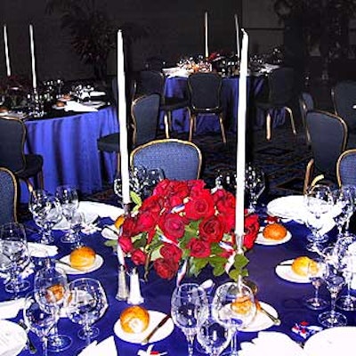 Atlas used lush red roses as centerpieces on tables decorated with blue tablecloths and white candles and napkins.